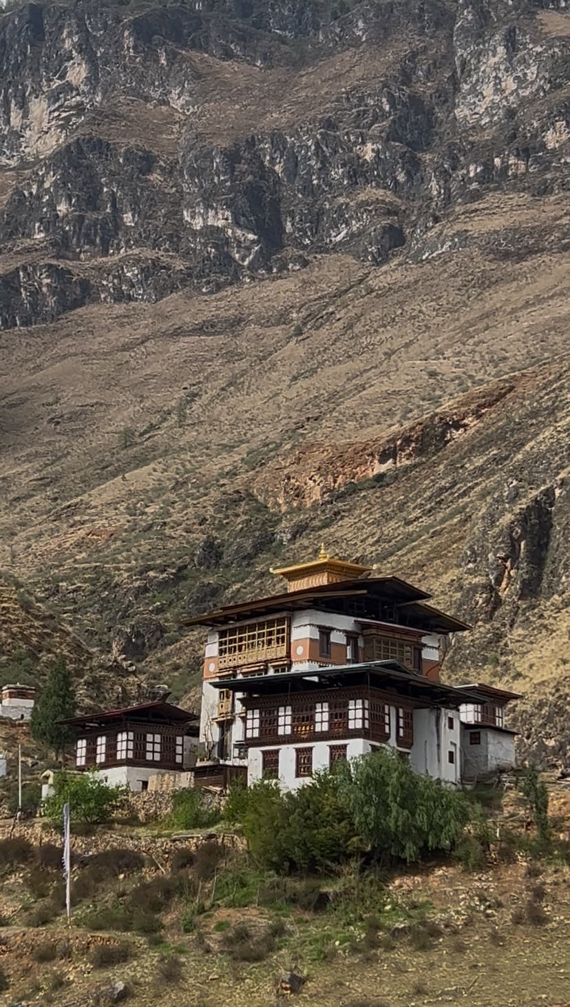 A monastery built into a dark cliff face, lit against the surrounding rock.